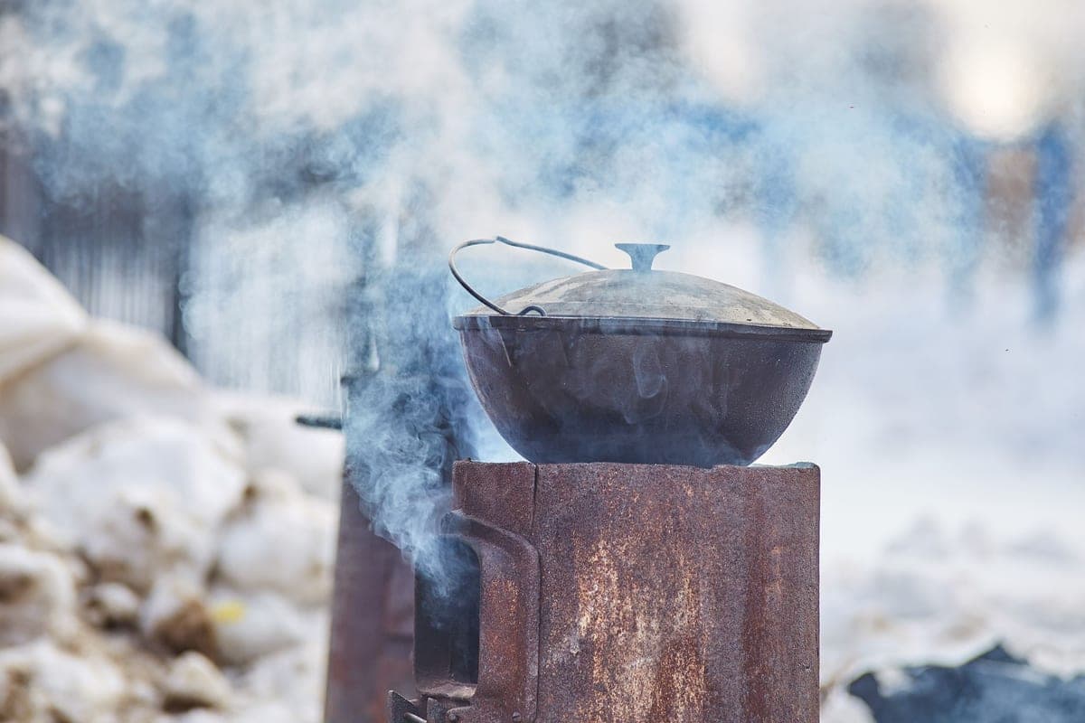 A cast iron dutch oven with the lid off on a rustic wood table